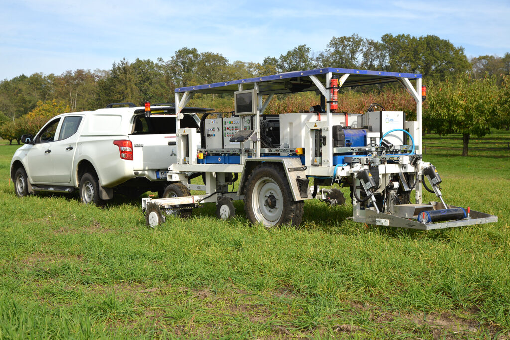 Ein Fahrzeug mit einem angehängten Messwagen fährt über ein Feld, Sensoren erfassen die Bodenbeschaffenheit