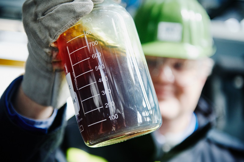 Ein Chemiewerker schüttelt eine Flasche mit verflüssigtem Kunststoff: chemisches Recycling für Mischplastik