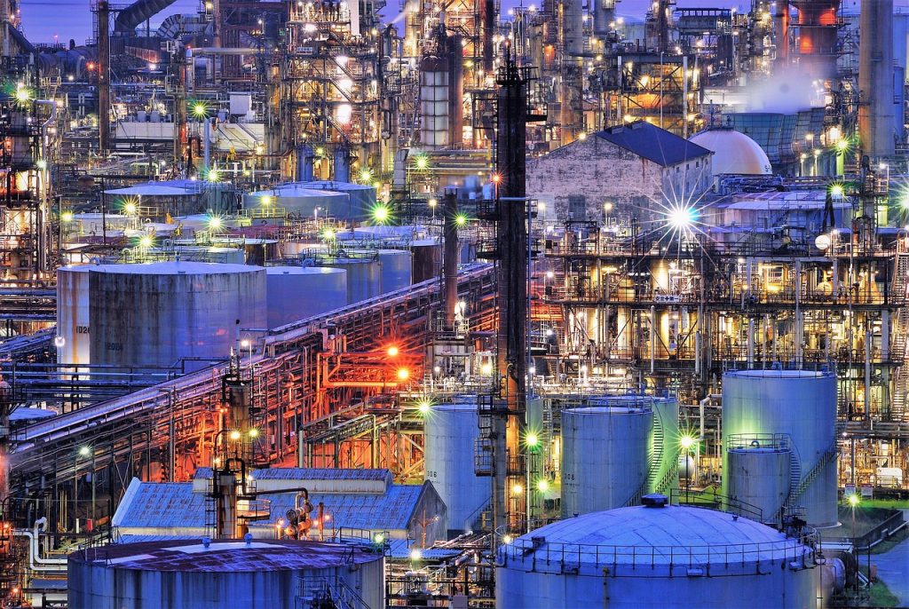 Öl-Raffinerie bei nächtlicher Beleuchtung - vor dem Weltklimagipfel in Dubai steht die Öl- und Gasindustrie am Pranger
